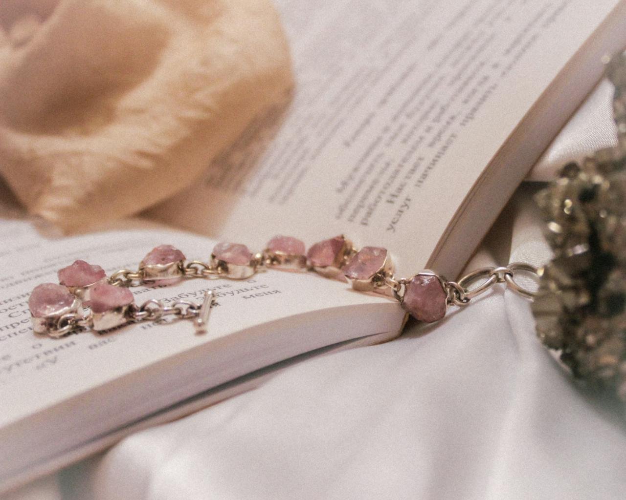 A pink crystal bracelet elegantly laid on an open book conveys beauty and sophistication.